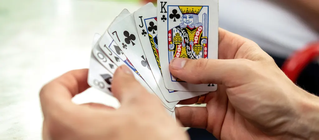 Römi szabályok útmutató, játékos kézben tartott kártyalapokkal, játék közbeni pillanat