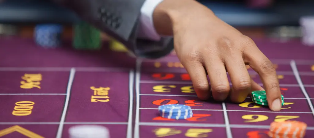 J&aacute;t&eacute;kos keze zsetonokat helyez el a rulettasztalon, amely j&oacute;l szeml&eacute;lteti, hogy kezdők&eacute;nt &eacute;rdemes elker&uuml;lni ruletten a meggondolatlan &eacute;s t&uacute;l kock&aacute;zatos t&eacute;teket